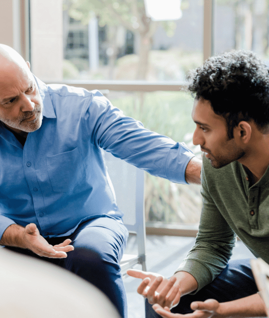 A mature man and a younger man talking during addiction group therapy