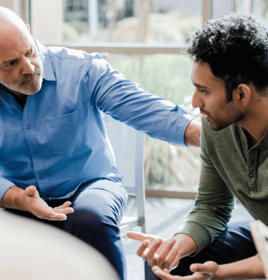 Senior man talking to a younger man at a medication-assisted treatment center