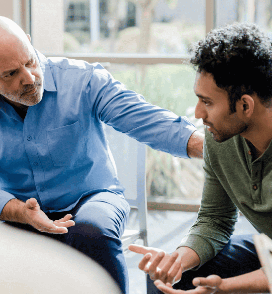 A young man and a senior man talking during group mental health IOP therapy