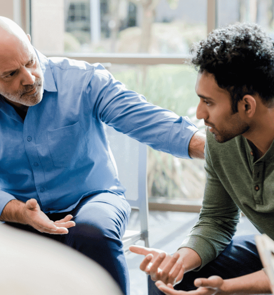 Senior man listening to a younger man during PHP dual diagnosis therapy